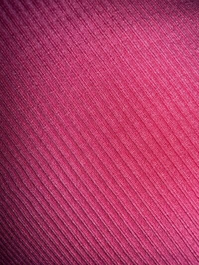 Close-up of pink fabric with diagonal ribbed texture.